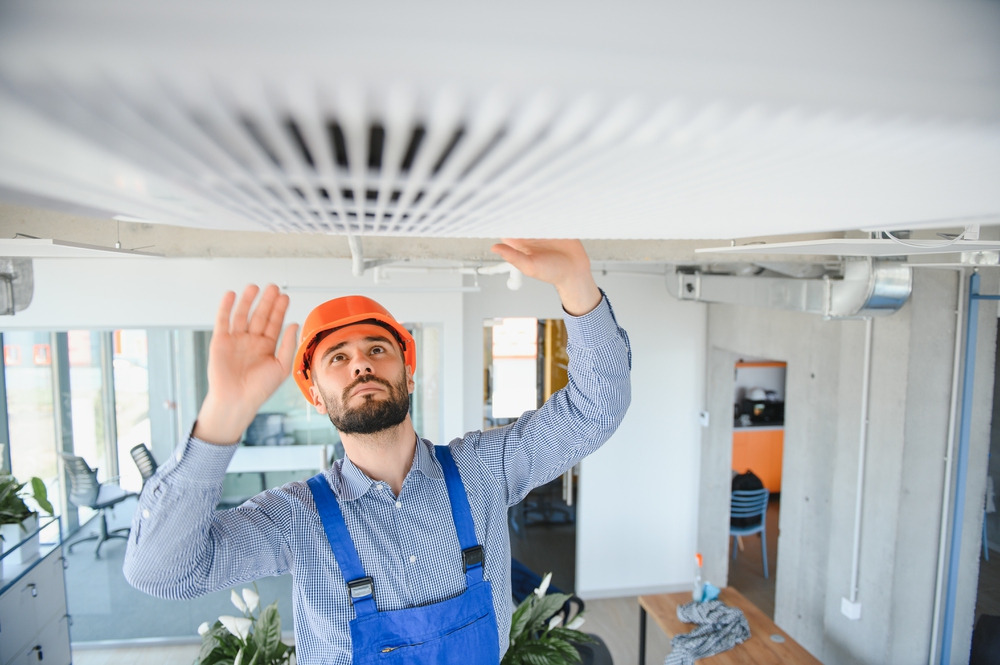 technician service checking and repairing air conditioner indoors.